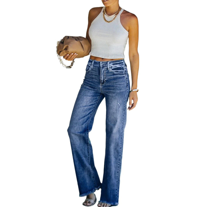 Woman wearing white sleeveless crop top, high-waisted wide-leg blue jeans, holding brown clutch bag