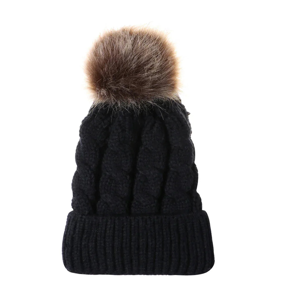 Black cable knit winter hat with large brown faux fur pom pom on top