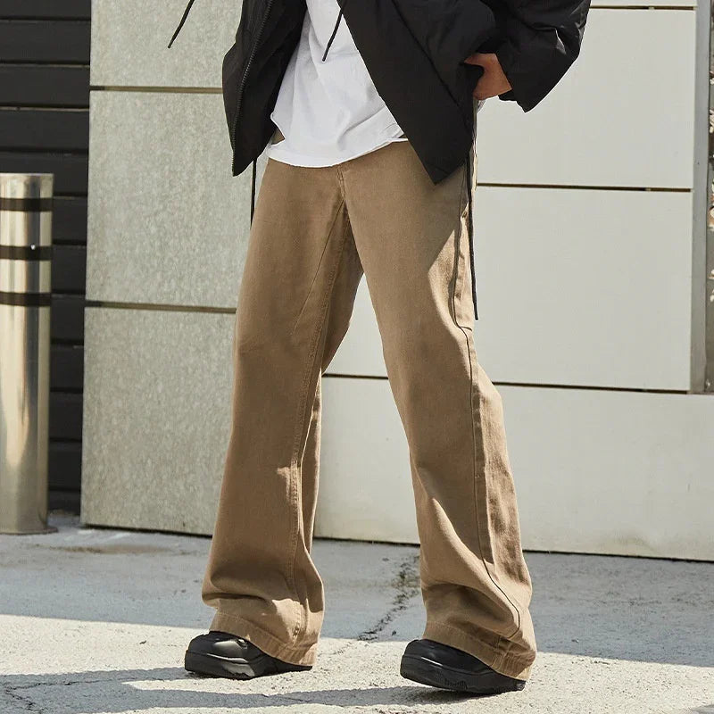 Person wearing beige wide-leg pants, black sneakers, white shirt, and black jacket outdoors