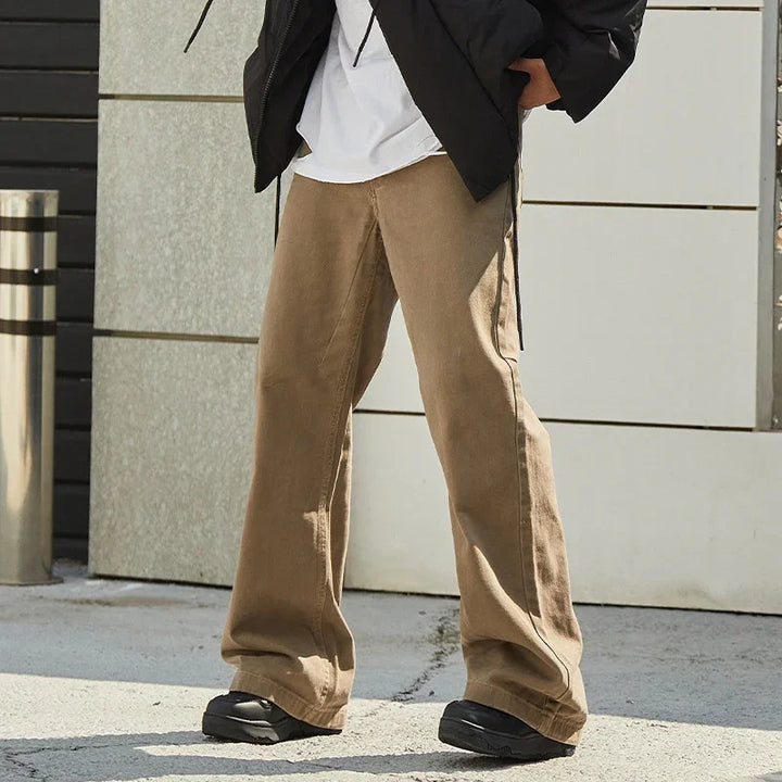 Model wearing loose-fit brown wide-leg pants with black sneakers and a black jacket outdoors