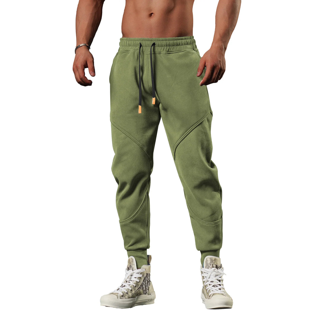 Athletic man wearing olive green jogger pants with black drawstrings and white high-top sneakers