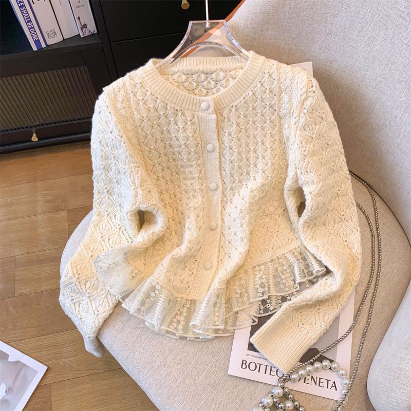 Cream knit cardigan with lace trim and pearl buttons on beige chair with fashion magazine and pearl chain