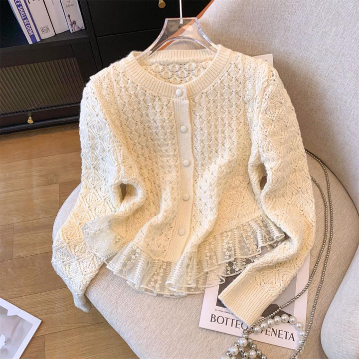 Cream knit cardigan with lace ruffle hem and pearl buttons on beige chair with pearl necklace