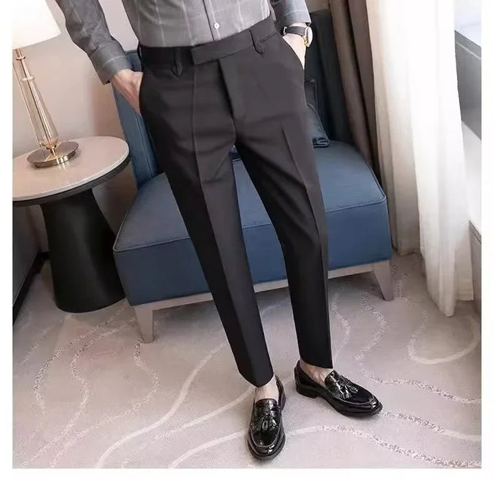 Man wearing tailored black dress pants and black tassel loafers standing in modern room