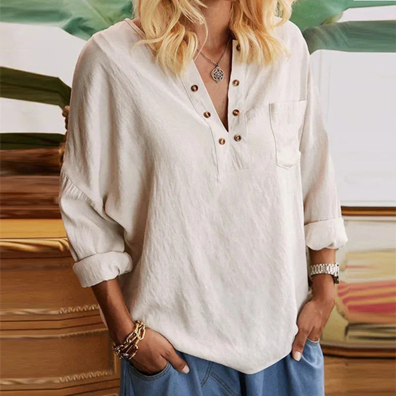 Woman wearing casual cream buttoned long sleeve blouse with rolled cuffs and blue pants