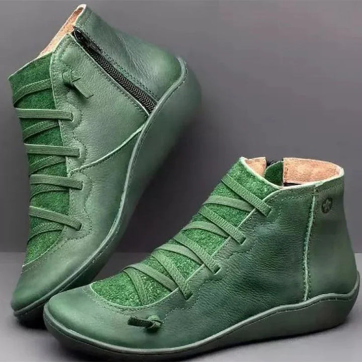 Green leather ankle boots with side zipper and textured front panel on gray background