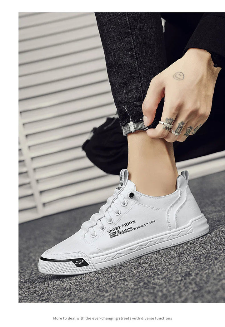 Close-up of white casual sport shoes with black text worn with black ripped jeans