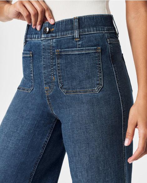 Close-up of high-waisted dark blue denim jeans with front patch pockets and button closure