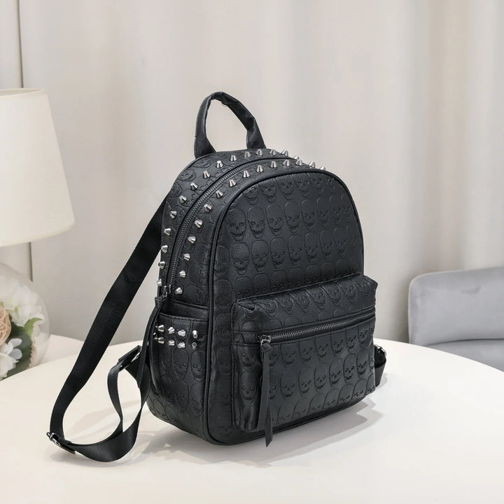 Black leather backpack with embossed skull pattern and silver studs on white table