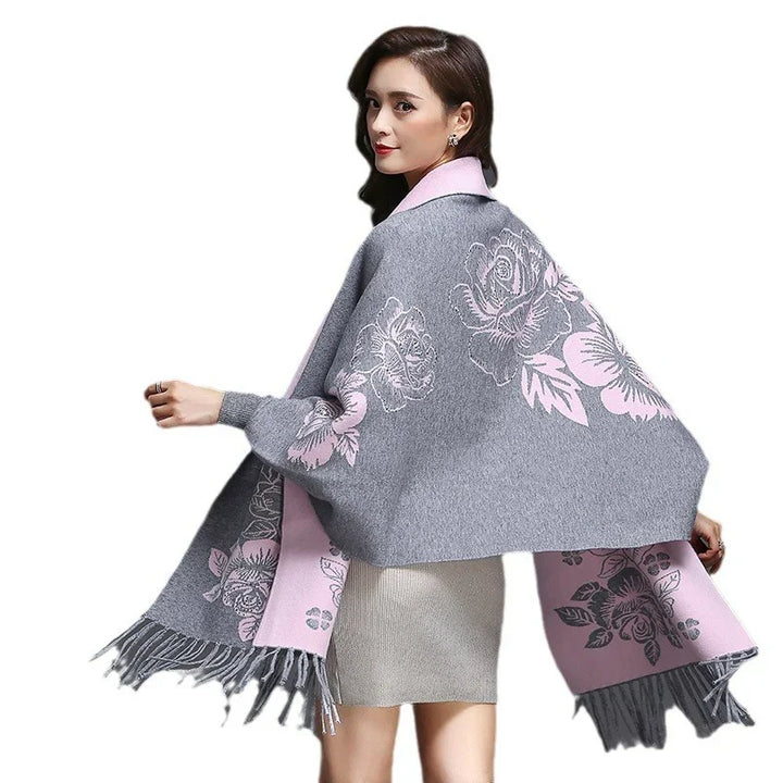 Woman wearing grey and pink floral patterned fringed shawl over light dress on white background
