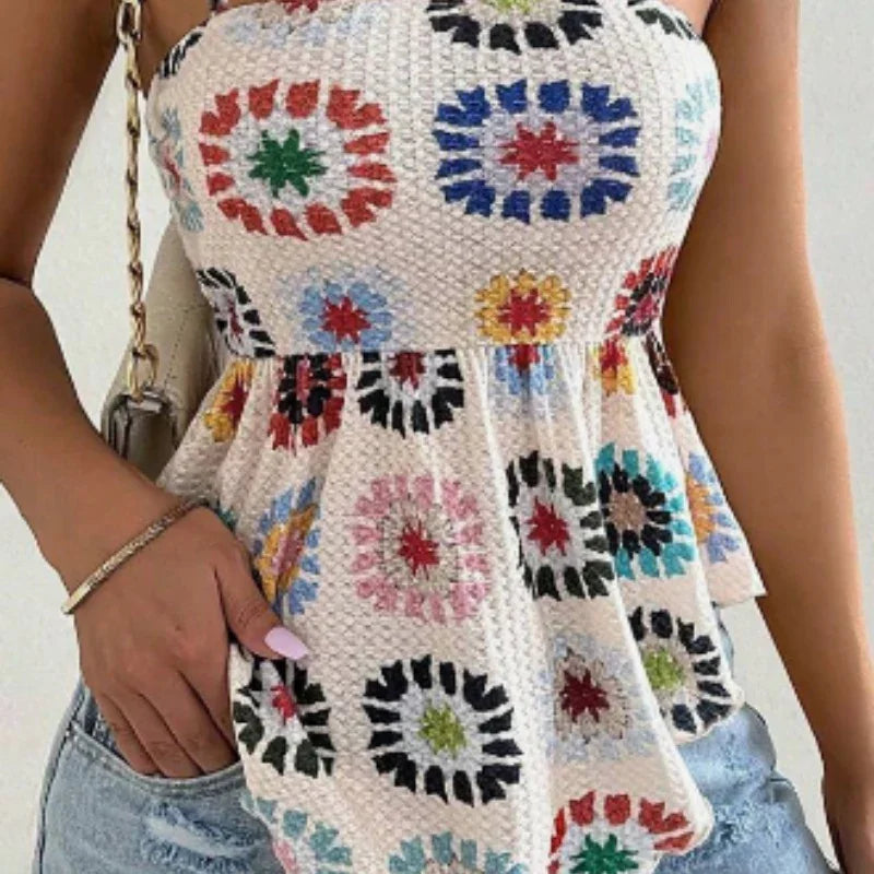 Woman wearing a colorful crochet crop top with floral square patterns and blue denim shorts