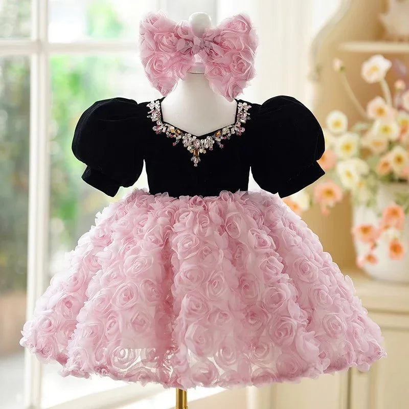 Elegant baby dress with black puffed sleeves, pink floral textured skirt, and jeweled neckline bow