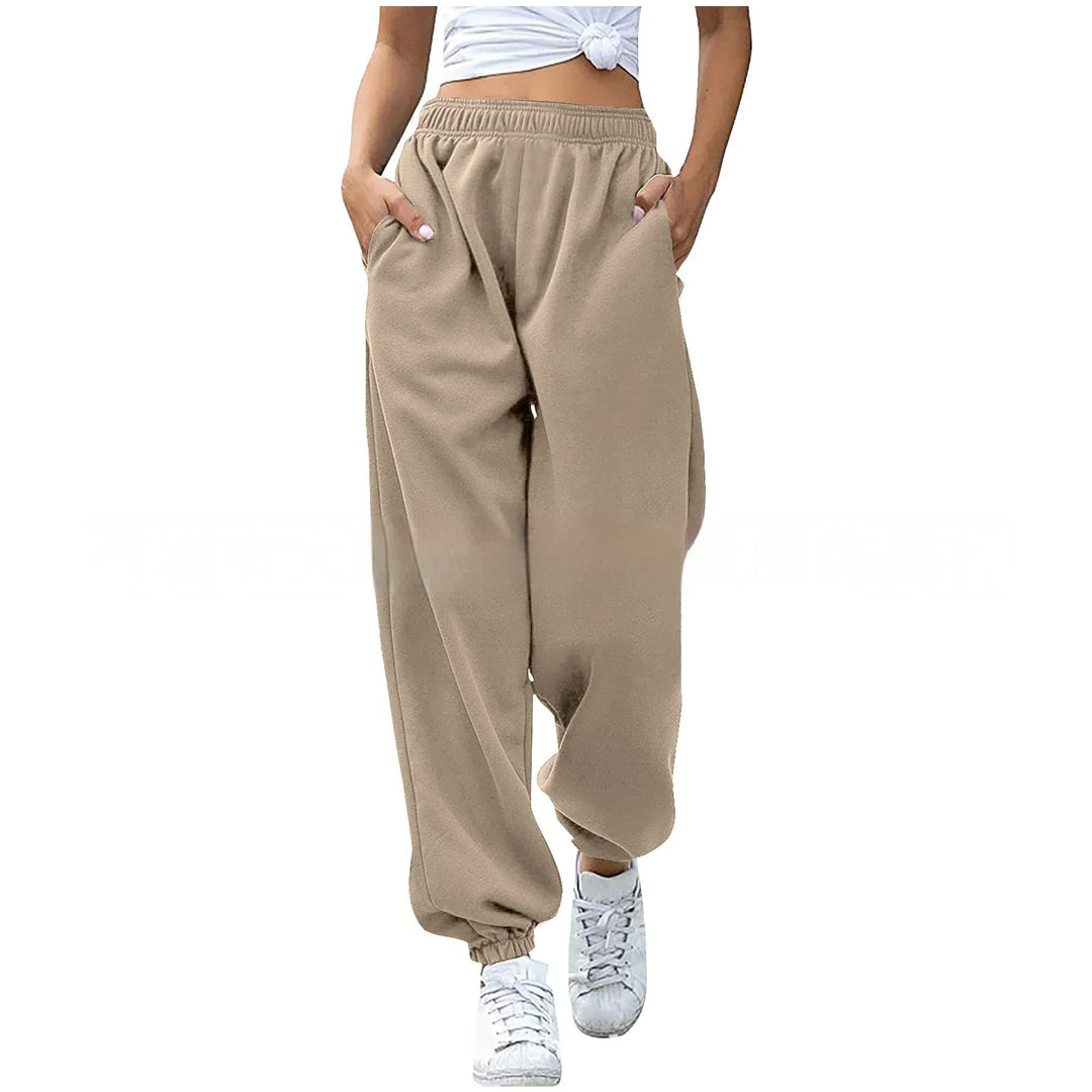 Woman wearing beige loose fit jogger sweatpants with elastic waist and cuffs, paired with white sneakers