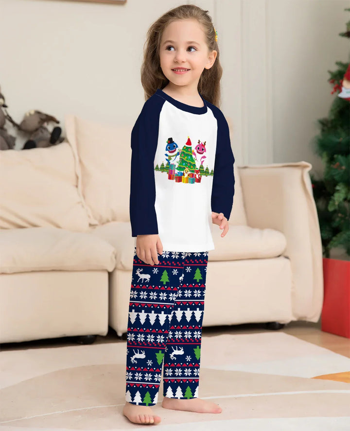 Smiling child in Christmas pajama set with festive tree, reindeer, and snowflake patterns