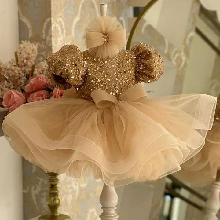 Elegant beige toddler dress with sequined bodice, puff sleeves, tulle skirt, and bow on mannequin