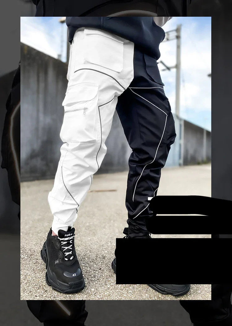 Black and white color-block cargo pants with reflective piping and black sneakers on urban street
