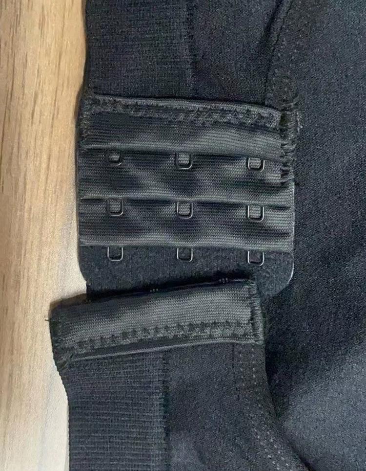 Close-up of black bra hook and eye closure on fabric against wooden surface