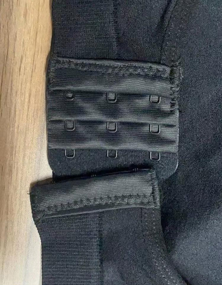 Close-up of black bra hook and eye closure on fabric against wooden surface