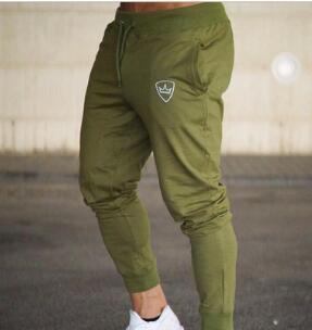 Man wearing olive green jogger pants with logo on thigh and white sneakers in urban setting