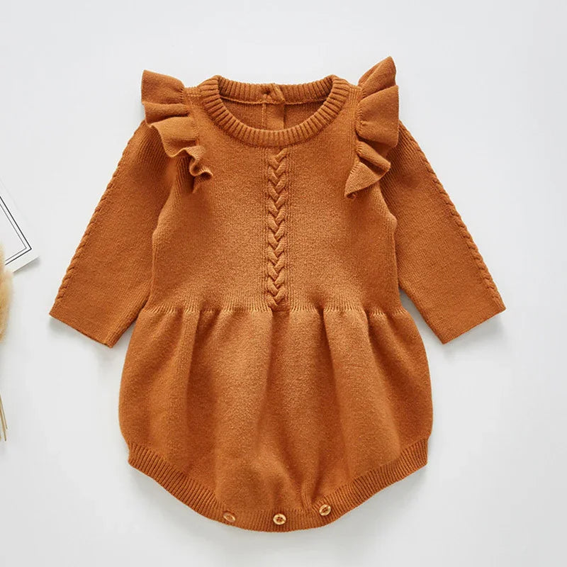 Rust orange baby knit romper with ruffled shoulders and braided central detail on white background