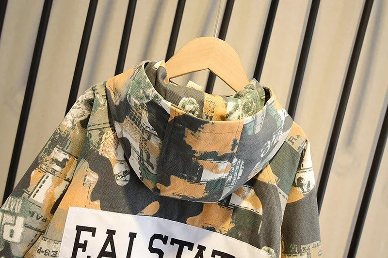 Camouflage print hoodie with abstract beige, green, and black patterns hanging on wooden hanger