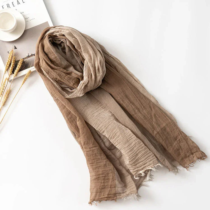 Lightweight brown gradient scarf with frayed edges on white surface with cup and dried wheat