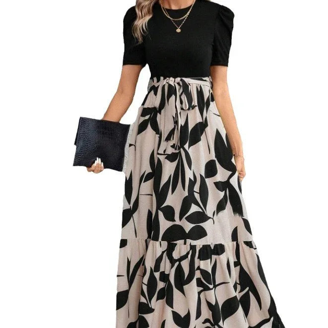 Woman wearing black puff-sleeve top with high-waisted beige skirt featuring large black leaf print, holding black textured clutch
