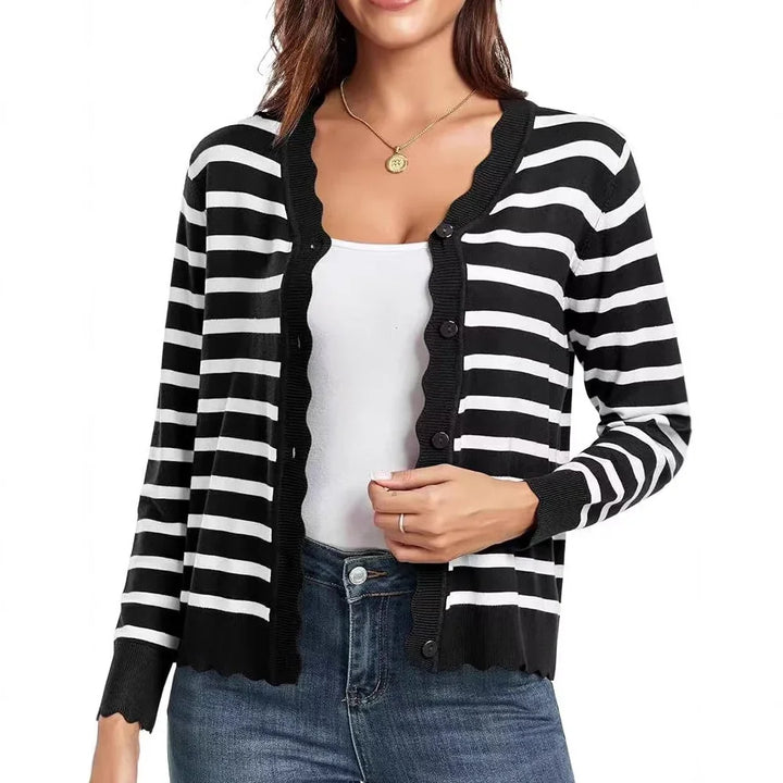 Woman wearing black and white striped button-up cardigan with scalloped edges, white tank top, and blue jeans