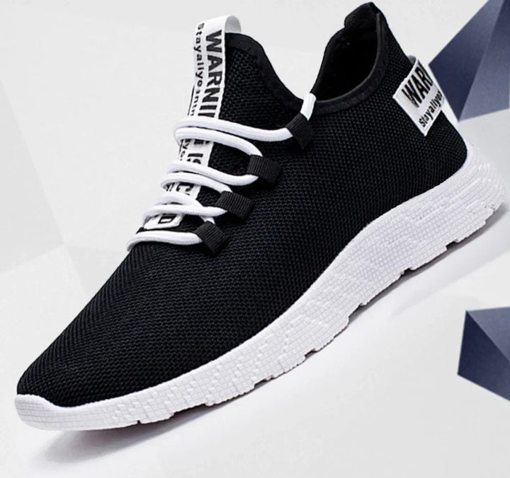 Black mesh sneaker with white sole and laces, featuring warning text on tongue and side tag