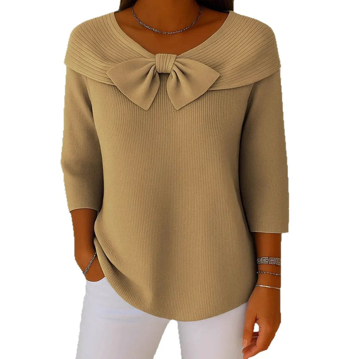 Woman wearing beige ribbed knit sweater with large bow neckline and three-quarter sleeves