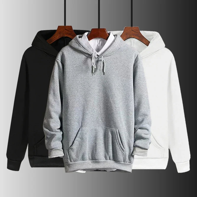 Three plain hoodies in black, gray with white shirt underneath, and white on wooden hangers
