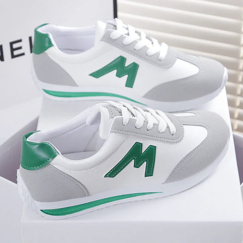 White and gray casual sneakers with green accents and 'M' logo, displayed on white boxes