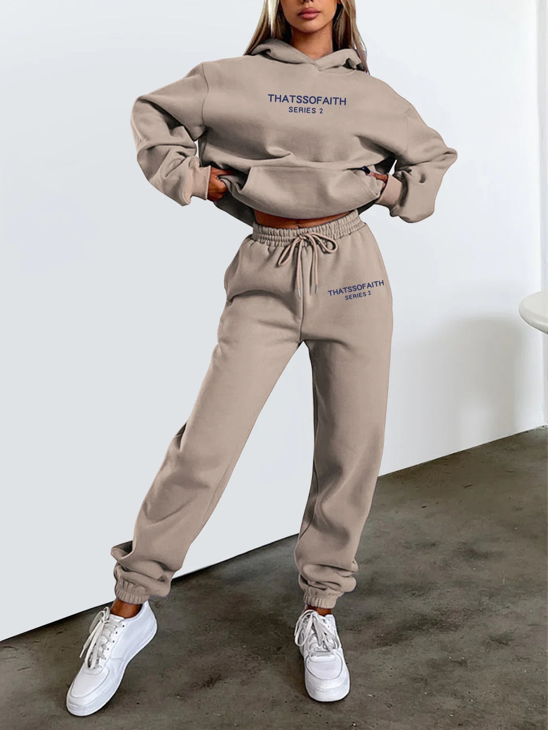 Woman wearing beige hoodie and joggers with THATSSOFAITH Series 2 text, white sneakers