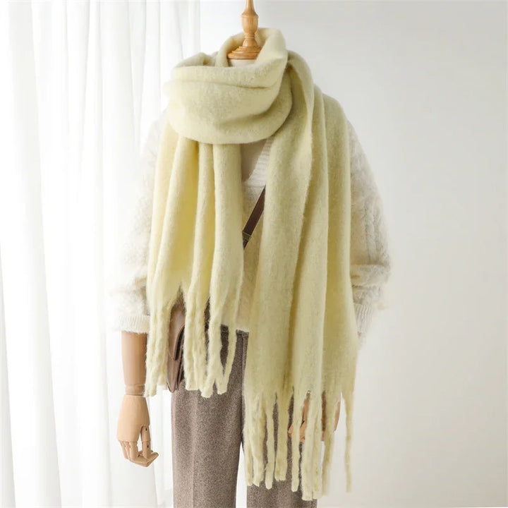 Soft cream-colored fuzzy scarf with fringes on mannequin wearing white knit sweater and brown pants