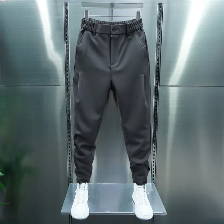 black jogger pants with elastic waistband and white sneakers on metallic display