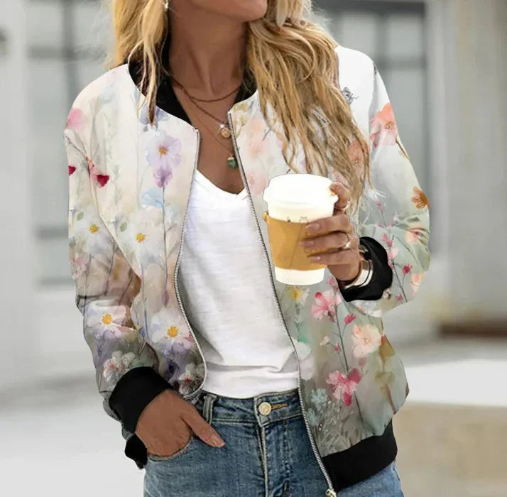 Woman wearing floral print bomber jacket over white top holding coffee cup outdoors