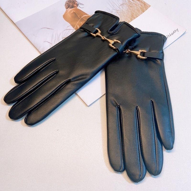 pair of black leather gloves with gold buckle detail on a white surface over a magazine