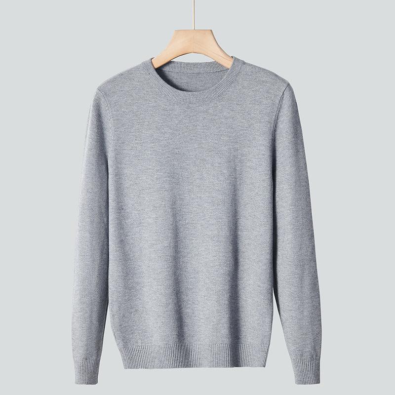 Light grey crewneck knit sweater hanging on wooden hanger against grey background
