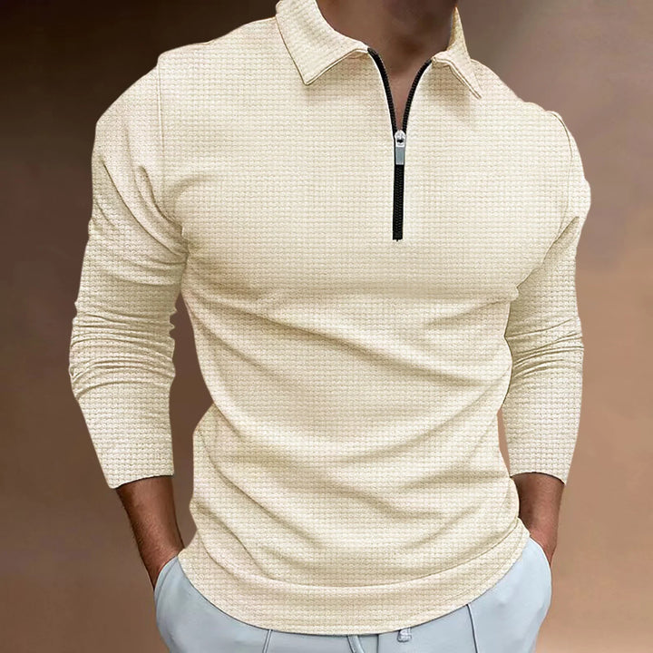 Man wearing beige textured long-sleeve polo with black zipper and light blue pants