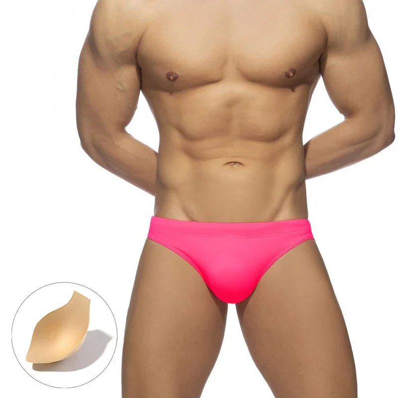 muscular male torso wearing bright pink swim briefs with removable beige pad displayed