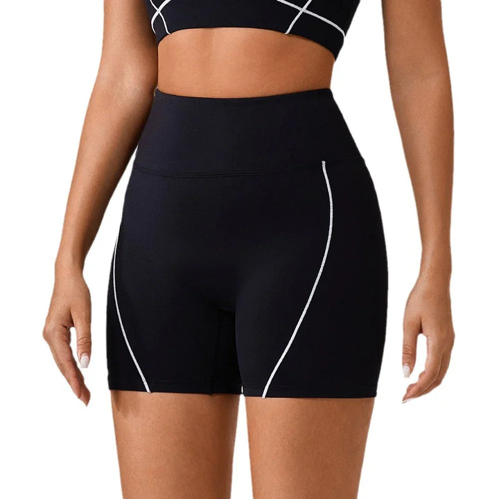 Close-up of woman wearing black high-waisted athletic shorts with white curved piping detail