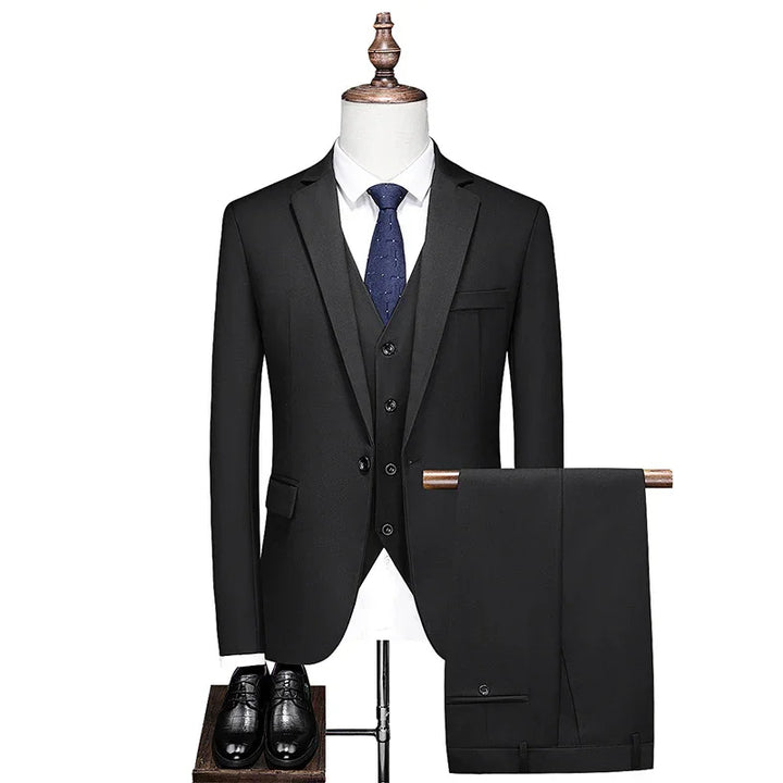 Black three-piece men's suit with blue tie, white shirt, black dress shoes on mannequin