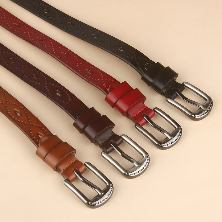 Four leather belts in black, red, dark brown, and tan with silver buckles on beige background