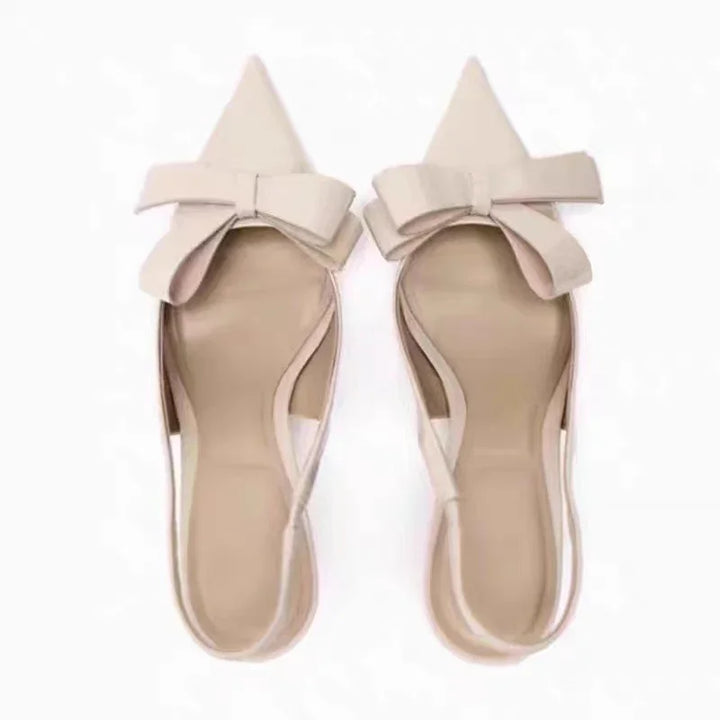 Pair of beige pointed-toe flat shoes with large decorative bows on top
