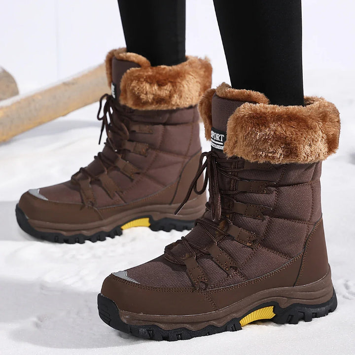 Brown winter hiking boots with fur lining worn on snow, featuring black soles and lace-up design