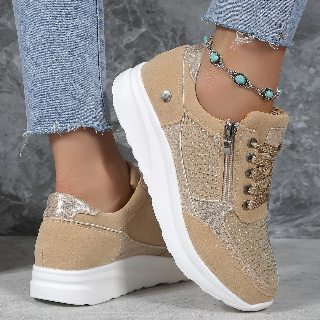 Beige suede sneakers with rhinestone details, side zipper, white soles worn with frayed blue jeans and turquoise anklet