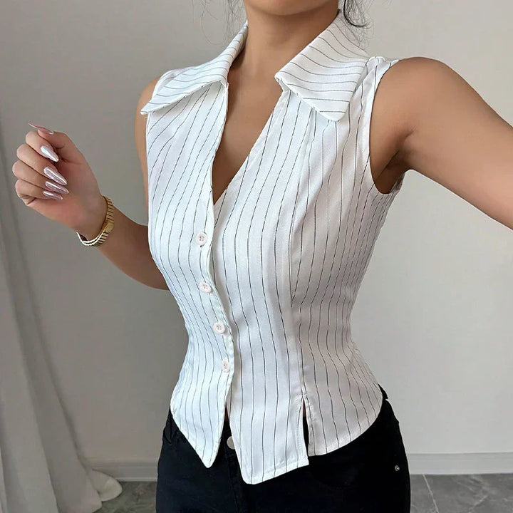 Woman wearing fitted sleeveless white pinstripe blouse with collar and buttons, paired with black pants