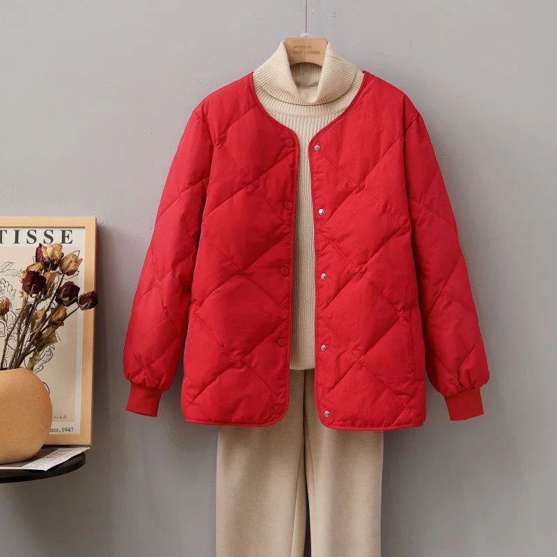 Red quilted jacket over beige turtleneck sweater and pants displayed on hanger in minimalist setting