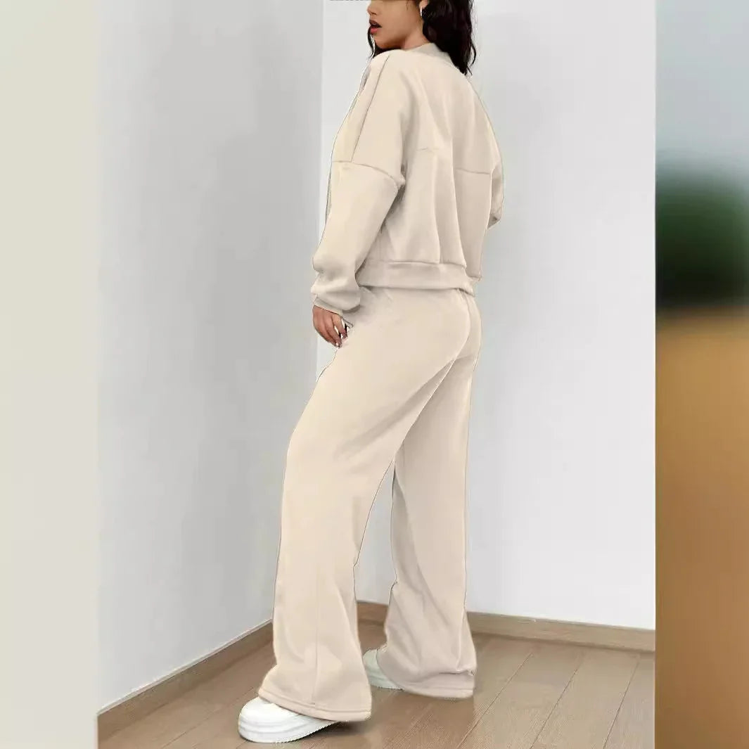 Woman in beige oversized sweatshirt and wide-leg pants with white sneakers standing indoors