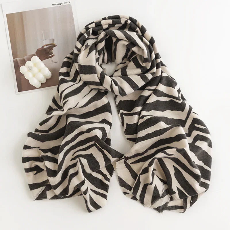 Black and white zebra print scarf with fringed edges on white background next to a photo and bubble candle